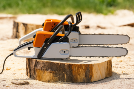 2 Motorsägen auf einem Baumstumpf